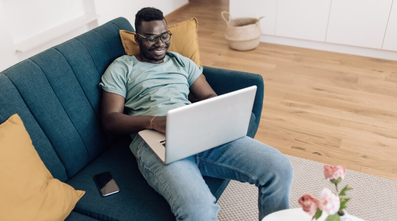 man sitting on the couch working on his laptop